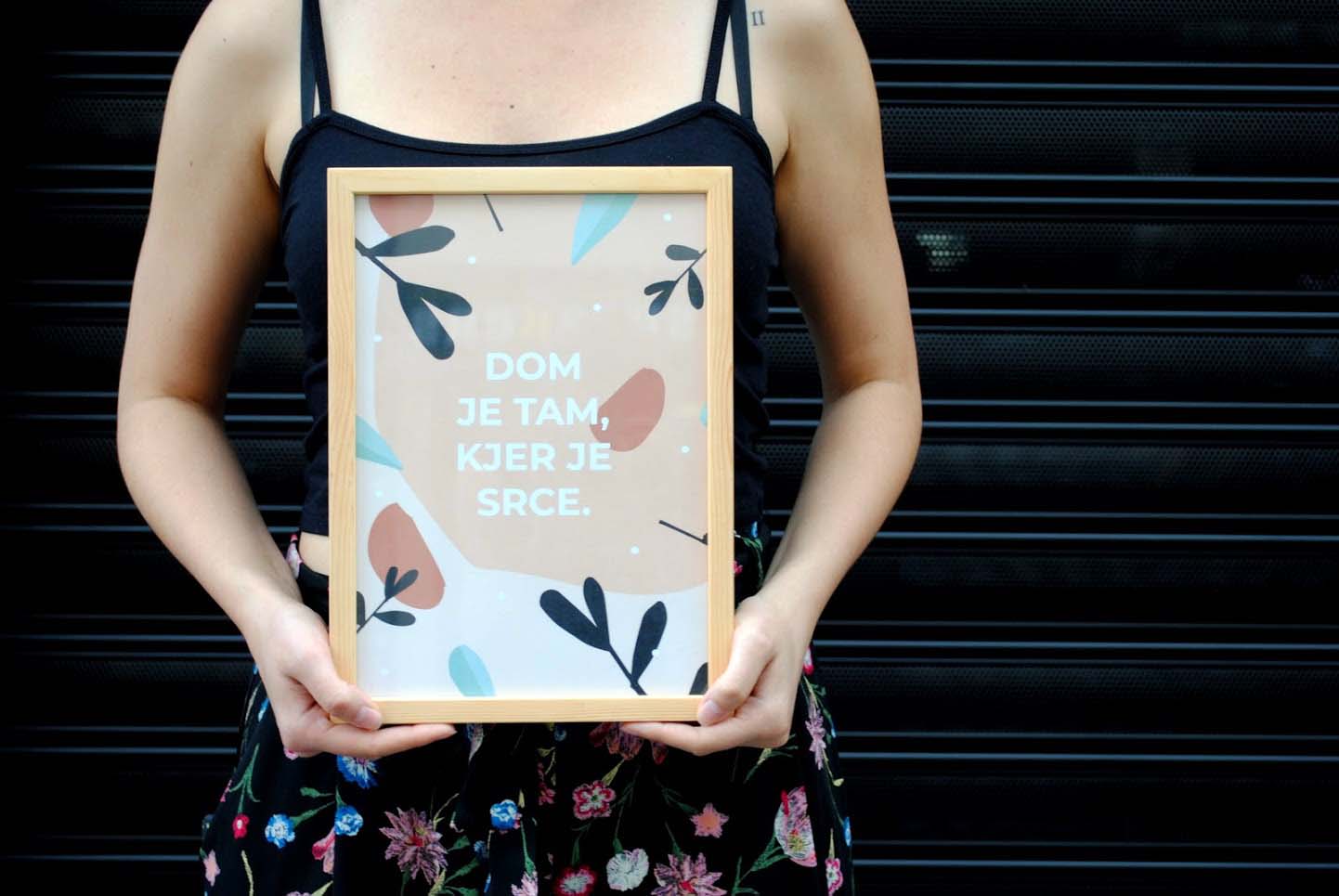 Uokvirjen svetlo roza plakat z napisom "Dom je tam, kjer je srce"
